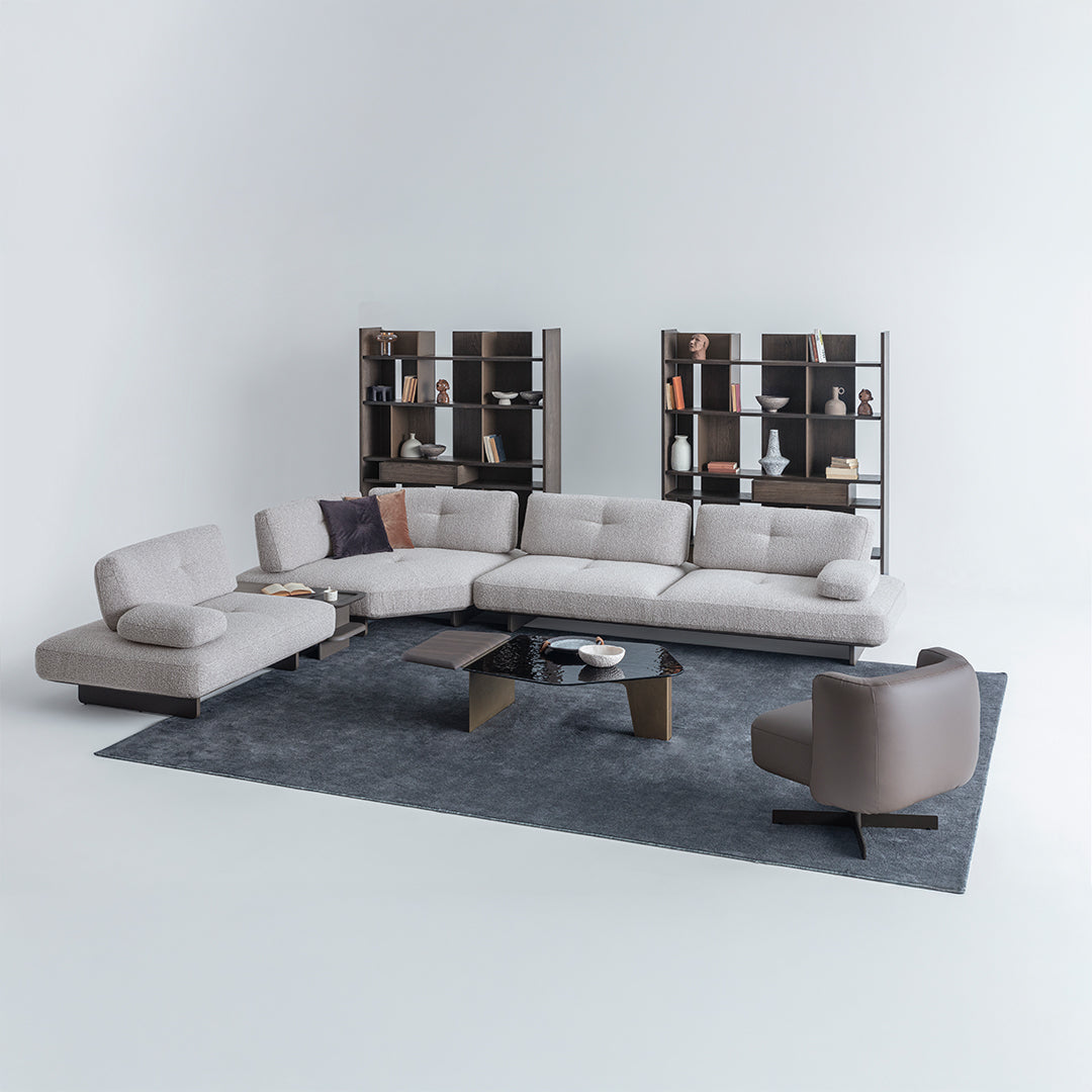 Modern living room setup with a sectional sofa, armchair, and coffee table on a gray rug.